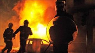 A policeman in front of a burning building and car in Croydon, South London