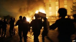 In this Nov. 3, 2005 file photo, French Riot police officers run past a burning car in Paris suburb, Aulnay-sous-Bois on the seventh day of unrest.