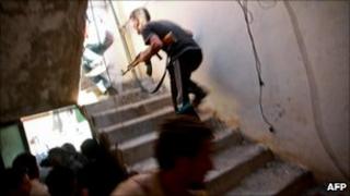 A rebel fighter runs up stairs during fighting in Zawiya, 13 August