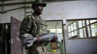 Ugandan soldier serving with the African Union Mission in Somalia carries a shell that were used by al-Shabab to make improvised explosive devices - August 2011
