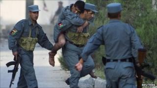 A wounded Afghan policeman is carried away from the site of an attack on offices belonging to the British Council in Kabul August 19, 2011.