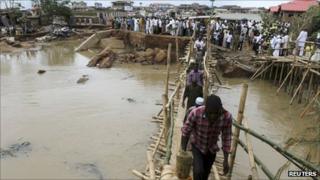 People queue to pass over a makeshift bridge in Ibadan, Nigeria (30 August 2011)