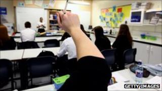 Pupils raise their hands in a classroom