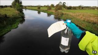 An Environment Agency worker holds a sample bottle of water from the River Trent in Staffordshire