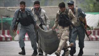 Afghan security forces carry the body of a colleague, who was killed during a gun battle with Taliban militants in Kabul, Afghanistan on Wednesday Sept. 14,2011