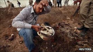 A man collects bones at the site of Abu Salim prison in Tripoli, 25 September 2011