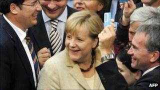 German Chancellor Angela Merkel (c) smiles surrounded by MPs holding their ballots on September 29, 2011 at the lower house of German parliament
