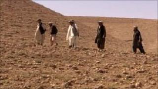 Men walking across dry hill