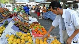 A fruit stall owner arranges his goods in a Rio de Janeiro market