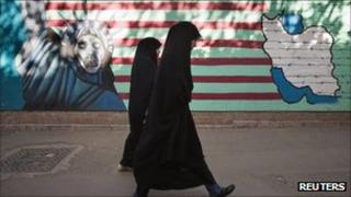 Two women in front of an anti-American mural in Tehran