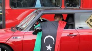 A man waves a Libyan flag from his car near the Libyan embassy in Knightsbridge on October 20, 2011