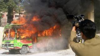 Pakistani media film a bullet-riddled burning bus in Quetta on October 4, 2011.