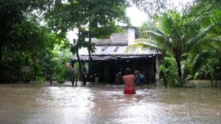 Abelardo Lopez wades towards his house in San Francisco Menendez