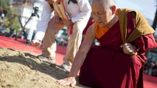 A monk touches the soil in Dharamsala