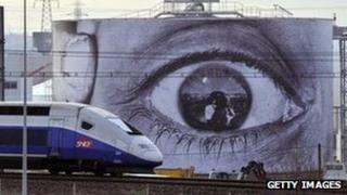 TGV train passes in front of billboard showing an enormous eye