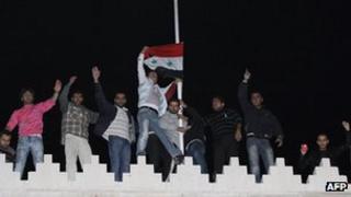 Pro-Syrian government supporters raise the Syrian flag on the roof of the Qatar embassy in Damascus on 12 November 2011