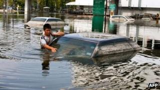 A man takes advantage of receded flood waters to check his car in the parking lot next to the Don Muang Airport on November 11, 2011.