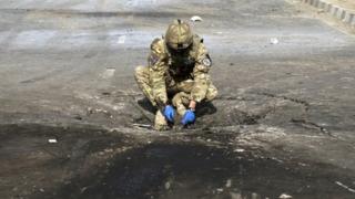 A foreign soldier investigates the crater caused by an explosion at the site of a suicide attack in Kabul October 29, 2011.