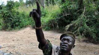 An SPLM-North fighter points toward an Antonov plane flying overhead moments before bombing the area in Kurmuk region of Sudan's Blue Nile state on 6 October 2011