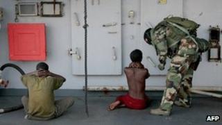 A soldier guards two suspected Somali pirates aboard a French warship (generic image)