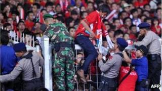 Indonesian security officials evacuate supporters of the Indonesia football team in Jakarta.