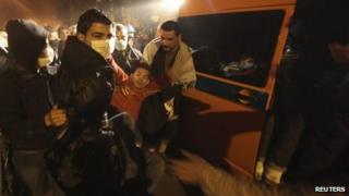Protesters assist an injured fellow protester into an ambulance after clashes with the army and riot police