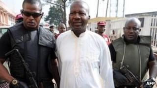 Baba Suwe escorted by armed guards (4 November 2011)
