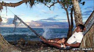 Man and his daughter relax in a hammock on the sea edge