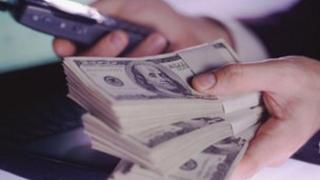 Man holding dollar notes and a mobile phone