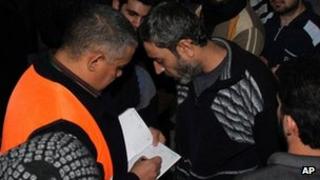 An Arab league observer writes the names of freed Syrian prisoners as they are released from Adra Prison on the north-east outskirts of Damascus