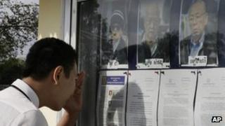 A student reads court documents displaying portraits of Khmer Rouge leaders Ieng Sary, from right, Khieu Samphan and Nuon Chea during a UN-backed war crime tribunal in Phnom Penh, Cambodia, on 16 January, 2012
