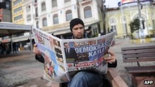 Man in Istanbul reading Turkish newspaper Hurriyet, showing the headline "He's slain democracy"