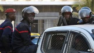 Riot policemen sit on the back of a pickup truck as they patrol the street in Dakar on 28 January 2012