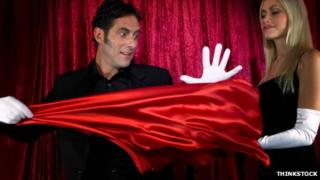 Magician performing a trick involving a red silk cloth