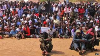 People watch Somali al-Shabab fighters on February 13, 2012, in Elasha Biyaha, in the Afgoei Corridor, during a demonstration to support the merger of al-Shabab and the al-Qaeda network