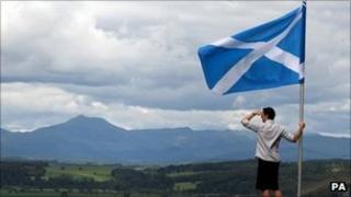 man next to saltire overlooking hills