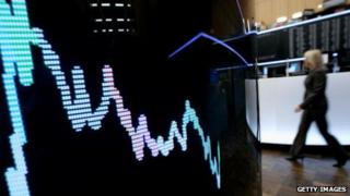 A trader walks past a display screen
