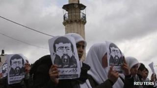 Students hold pictures of Palestinian hunger striker Khader Adnan in Nablus, the West Bank, 19 February