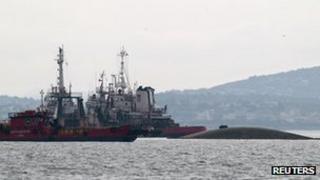 Two tugs alongside the nearly submerged ship