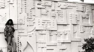 Artist Joan Smith in front of her sculpture, 'City People'