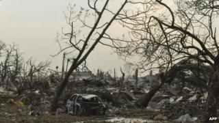 Smoke rises from the debris as a fire continues to burn in a military barracks, near an underground munitions depot, in Brazzaville, Congo Monday, 5 March, 2012.