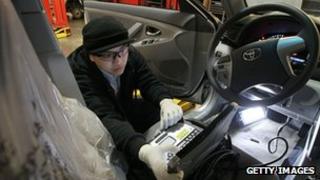 A worker checking brake pedals in a Toyota Camry car