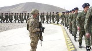 A US soldier watches members of the Afghan Public Protection Force arrive at the transition ceremony of private security forces to Afghan Public Protection Force (APPF) on the outskirts of Kabul