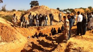 People gather at an excavated mass grave