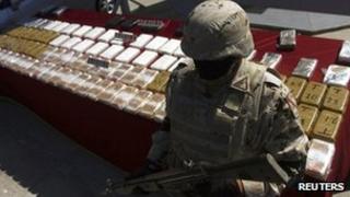 A soldier stands next to packages containing confiscated drugs during a presentation to the media in Tijuana, 14 March 2012