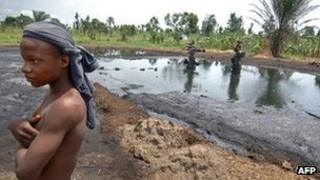 Boy stands near an abandoned oil well head leaking crude oil, 11 April 2007, in Kegbara Dere, Ogoni Territory