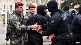 Член коммандос полиции США в масках рукопожатие с десантником в казарме Периньон после окончания осады в Тулузе, 22 марта
