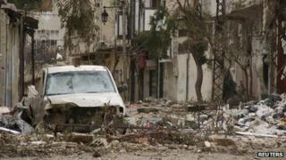 Damaged car and buildings in the Old City of Homs (30 March 2012)