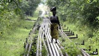 A woman walks along pipelines belonging to Shell in the Niger Delta, Nigeria (Archive shot 2006)