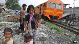 a squatter family walking along railway tracks in Jakarta running